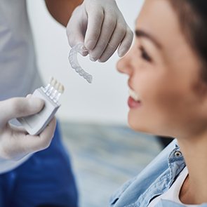 A dentist showing an Invisalign tray to a patient