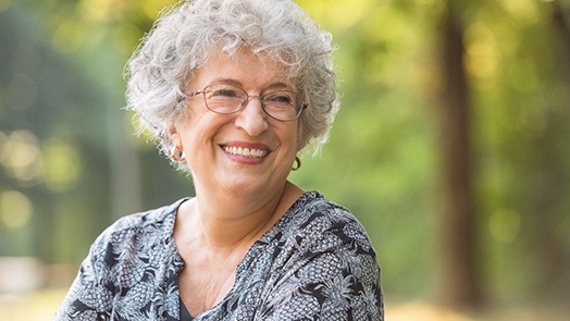 Senior woman with glasses smiling in park