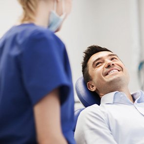 Dentist talking to smiling patient in treatment chair