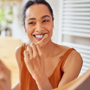 Woman smiling while brushing her teeth