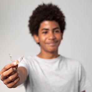 Teenage boy holding out an Invisalign aligner