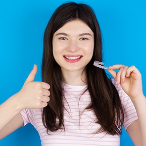 Teenage girl holding Invisalign and giving a thumbs up