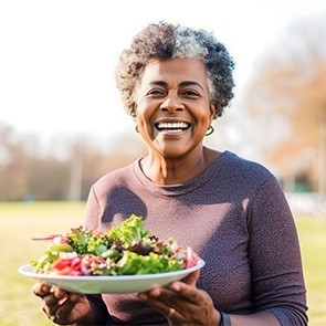 Smiling woman holding plate of healthy food outside