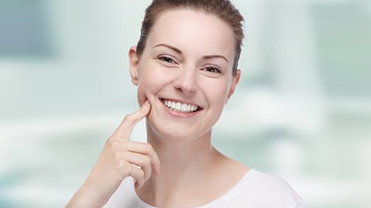 Happy young woman pointing at her teeth